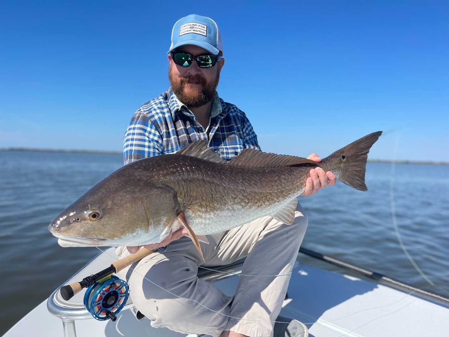 Philip holding a redfish on the bow of a skiff